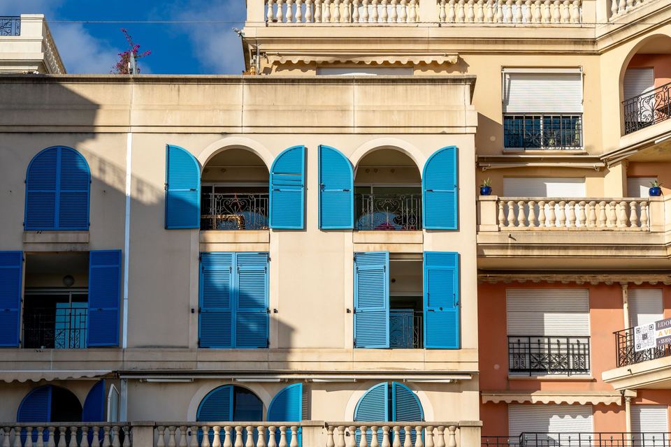 Immeuble balnéaire crème aux volets bleus et balcons en arcade